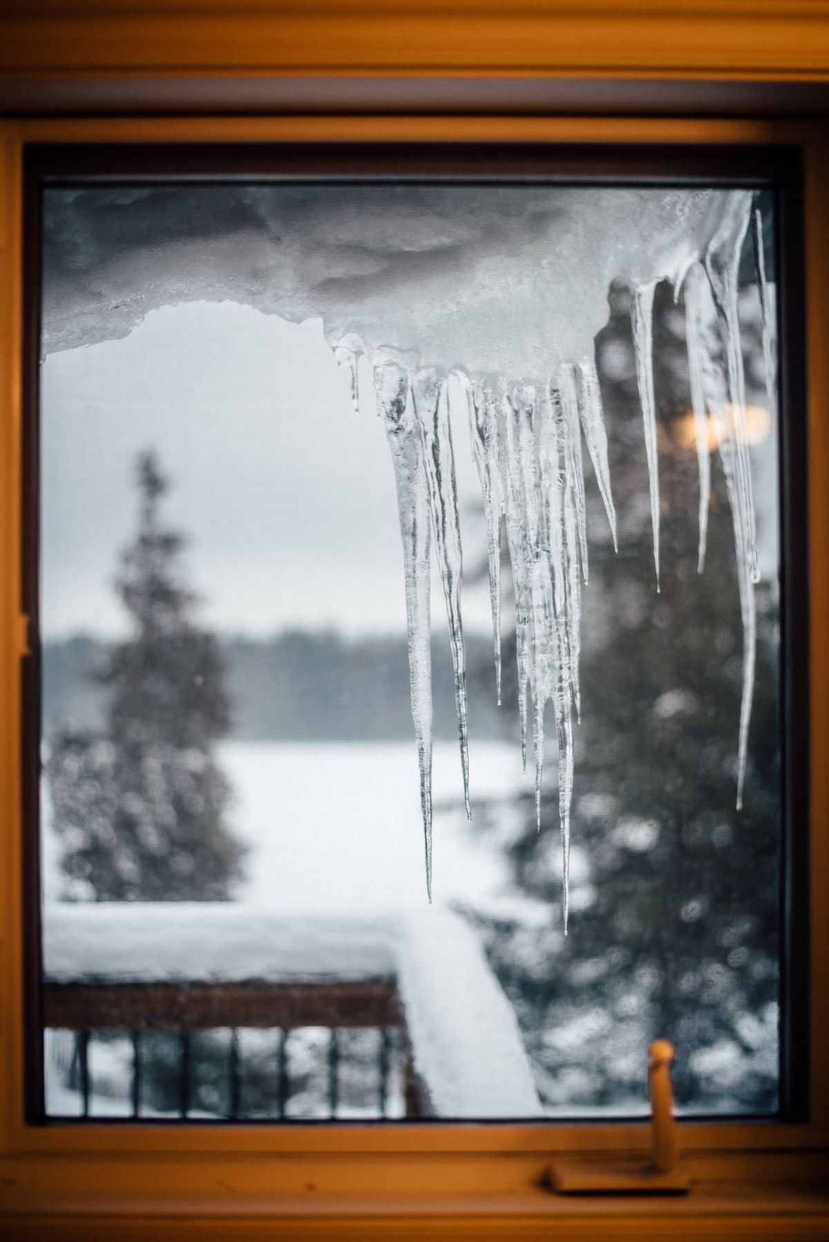 Icicles hanging from a window frame on a snowy winter day