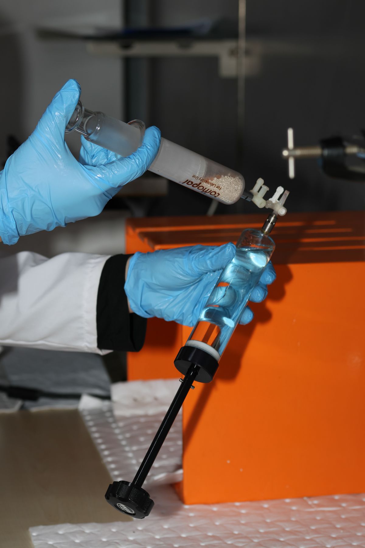 Scientist handling lab equipment while wearing gloves, illustrating the kind of materials testing used to measure snake plant fibre composite strength