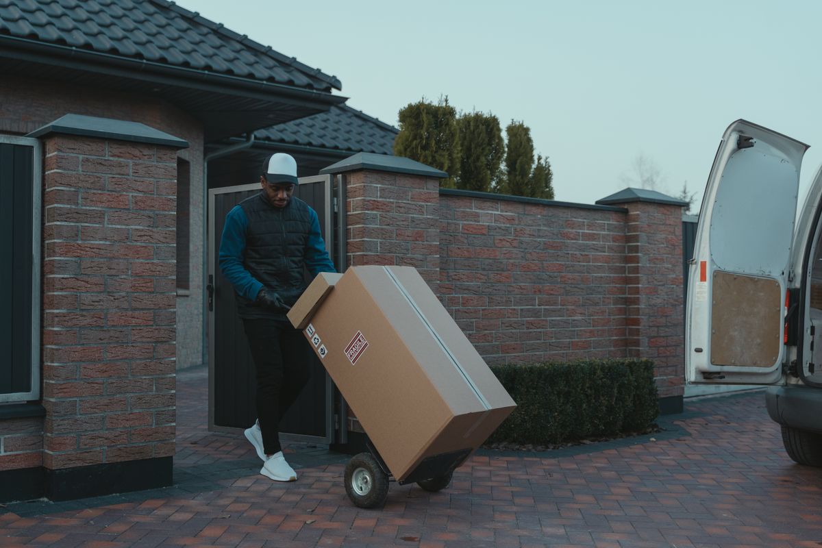 A professional delivery worker transporting a package with a hand truck