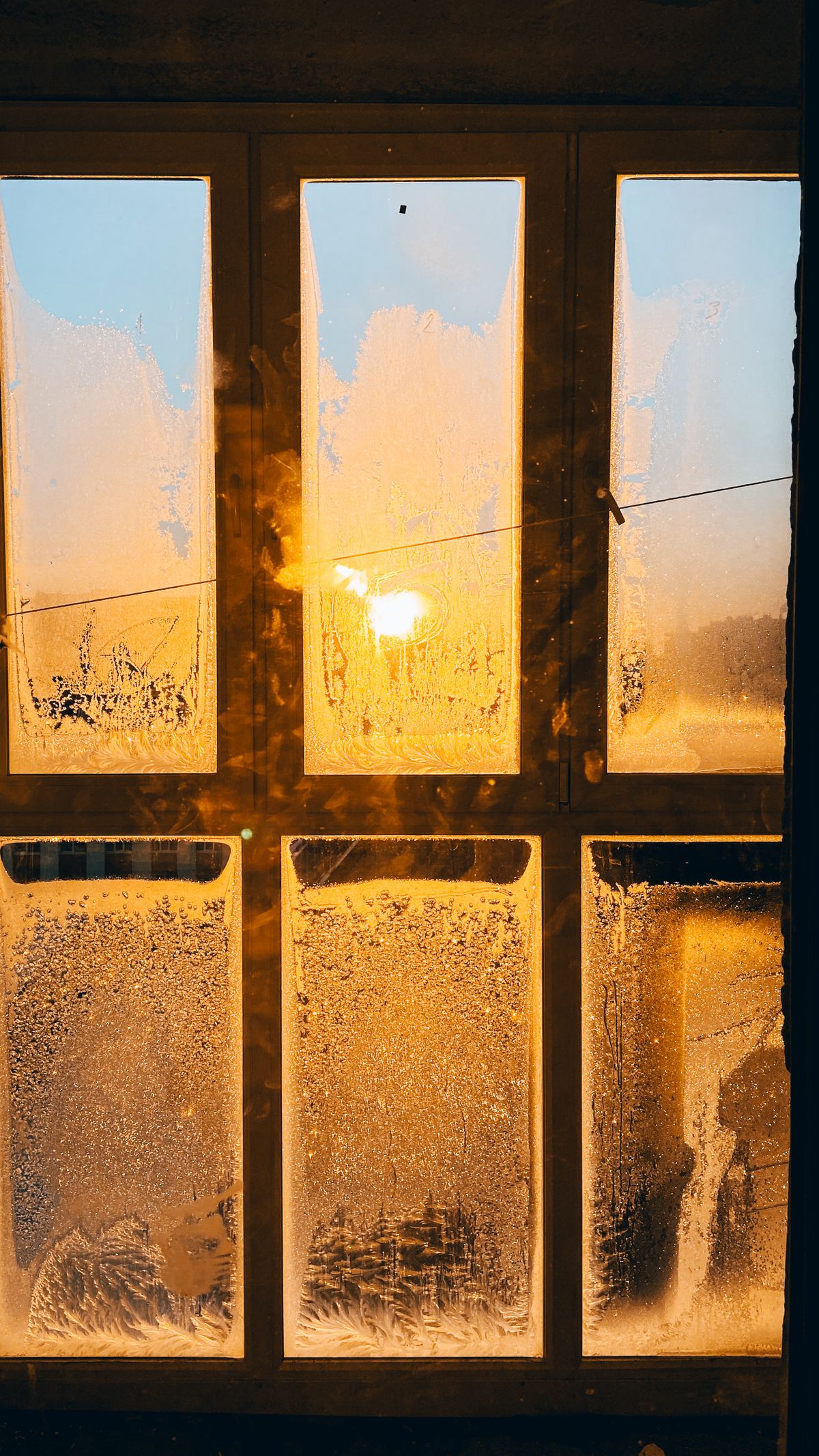 A frosty window glowing with warm sunlight during a winter sunrise